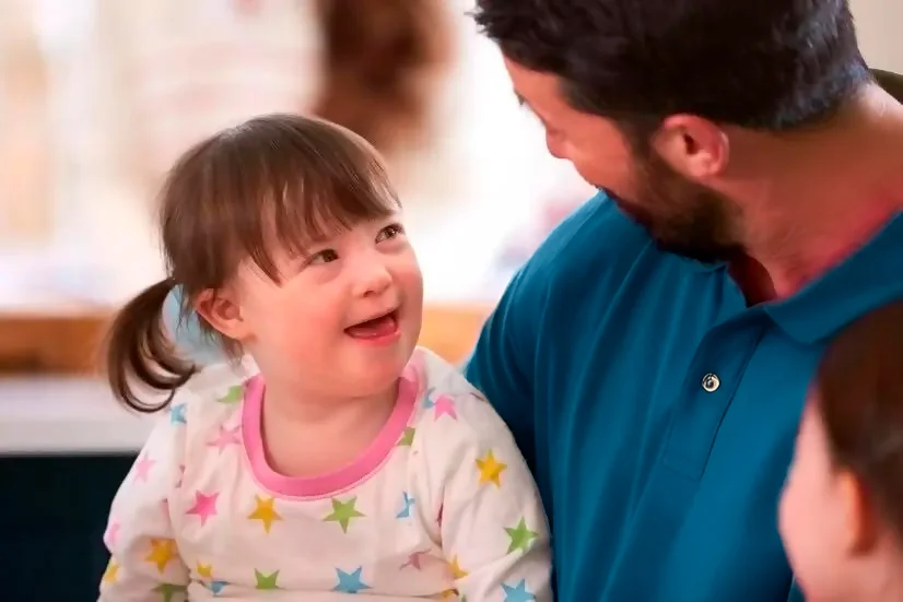 Niña con síndrome de Down sonriéndole a su padre.