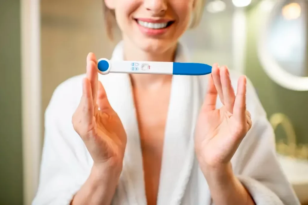 Mujer sonriente sostiene una prueba de embarazo entre sus manos