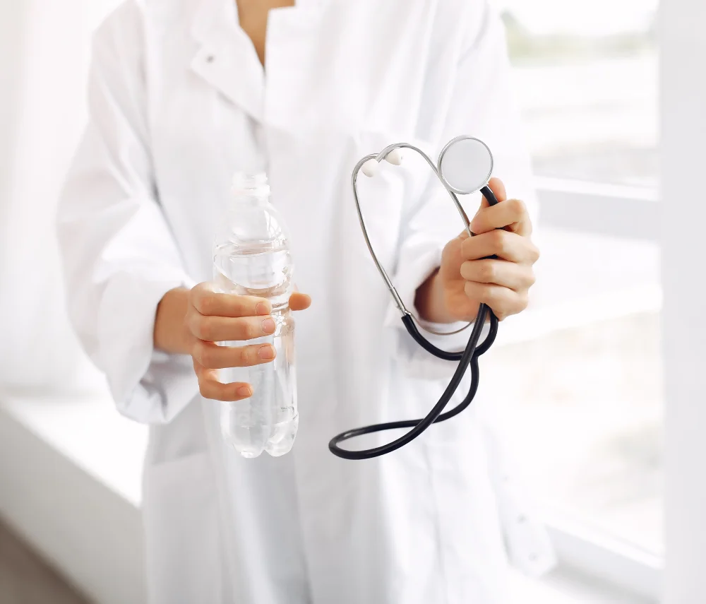 Una doctora con un estetoscopio y una botella de agua durante una asesoría en nutrición, destacando el rol de los nutriólogos para bajar de peso.
