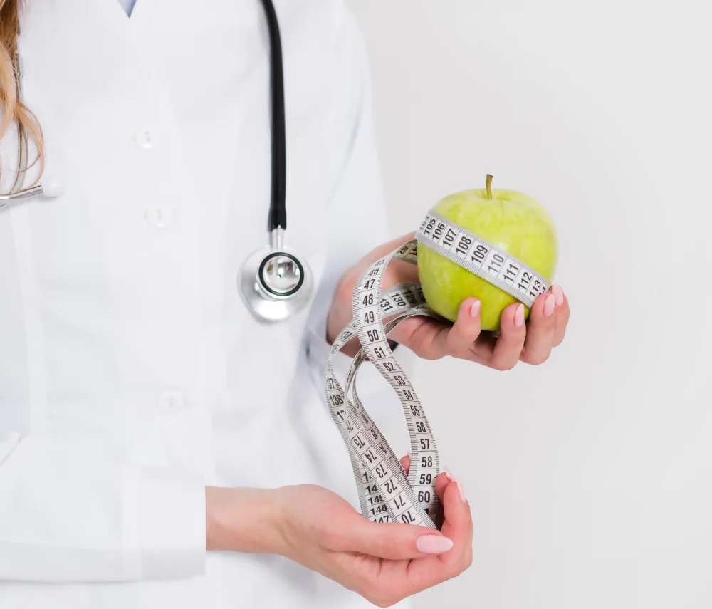 A doctor holds an apple and a measuring tape, illustrating the work of bariatric nutritionists in weight control.