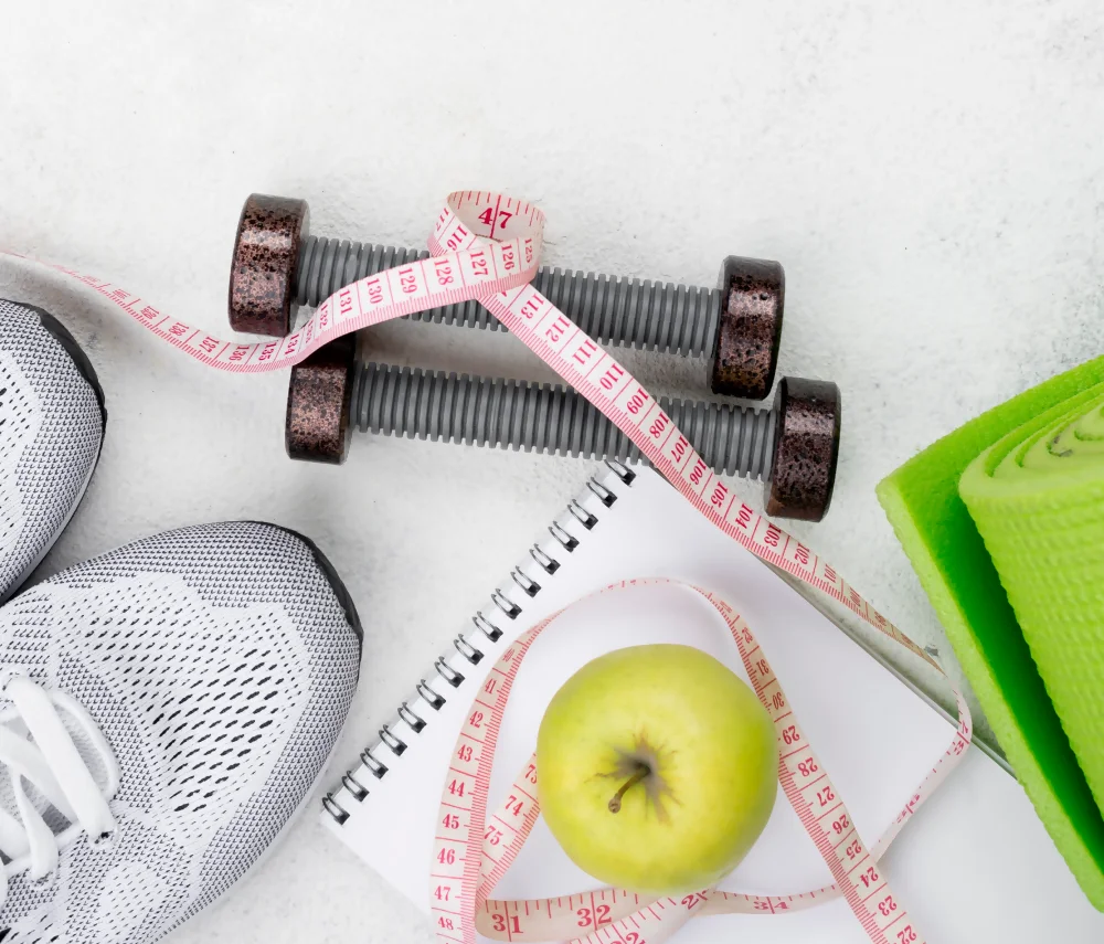 The image shows sneakers, weights, a measuring tape, an apple, and a yoga mat, related to sports medicine.