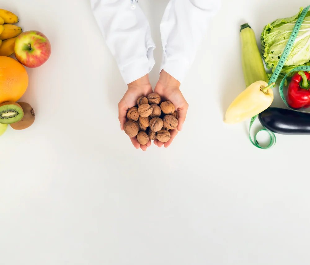 Una doctora muestra porciones de alimentos en una asesoría nutricional, con frutas, verduras y una cinta métrica.