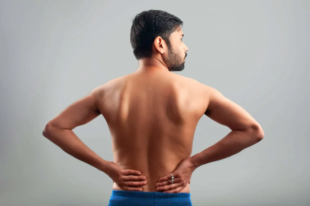 Hombre con escoliosis lumbar se masajea la espalda baja.