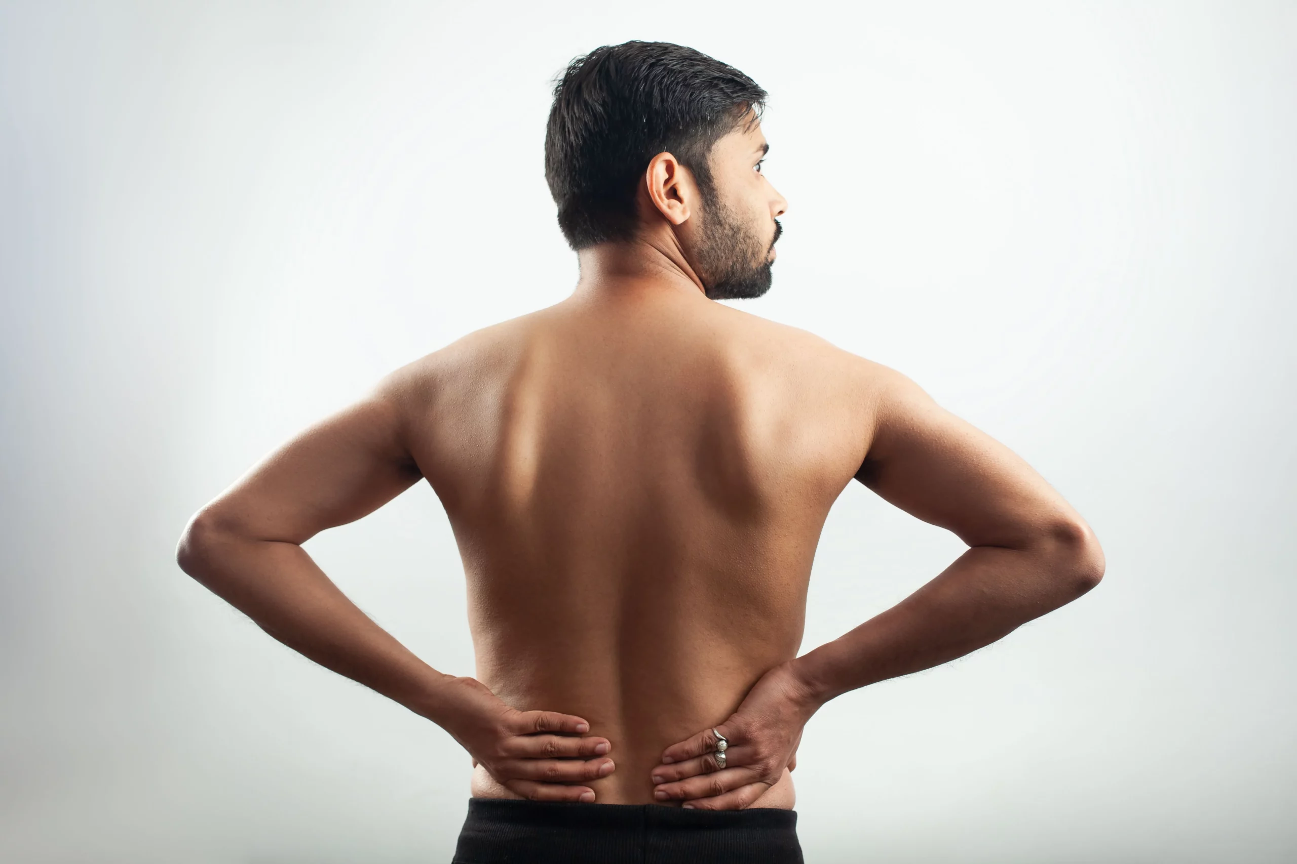 Hombre con escoliosis lumbar se masajea la espalda baja.