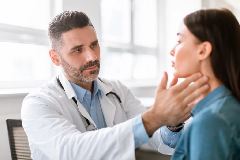 Médico endocrinólogo revisando la tiroides de una paciente. 