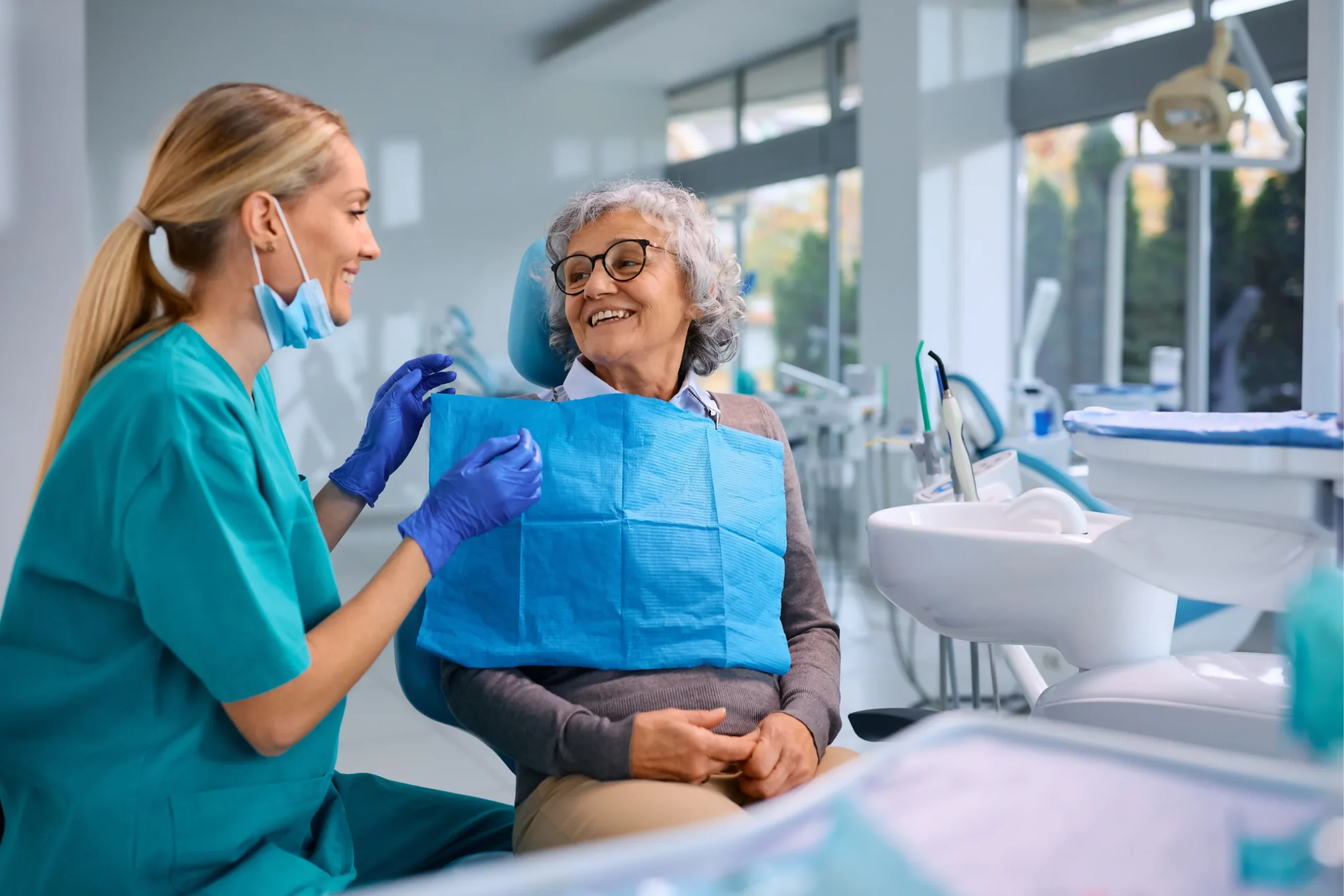 Mujer sonriendo mientras está recibiendo atención por parte de su dentista.