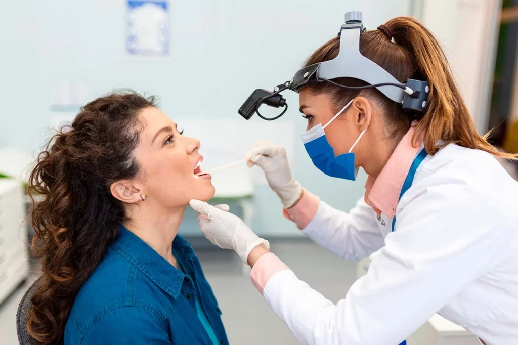 Mujer con faringitis aguda siendo revisada por su doctora.