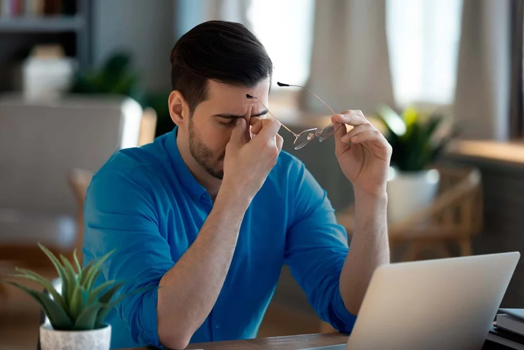 Hombre agotado con dolor de cabeza después de un largo día de estar frente a laptop 