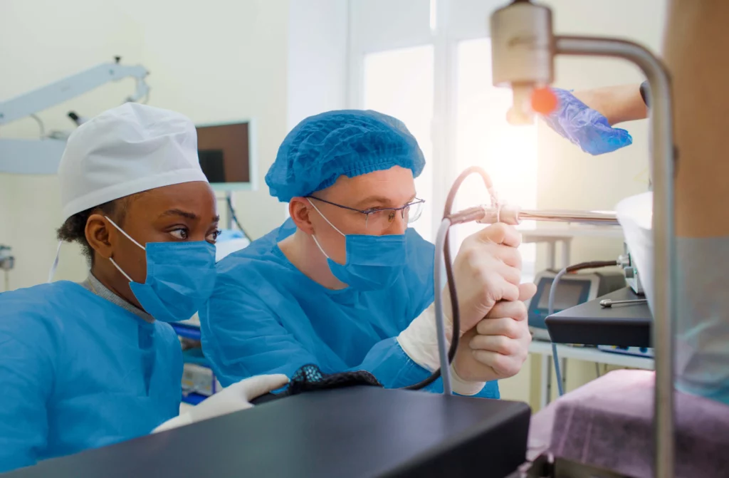 Médicos revisando el monitor mientras realizan una colonoscopia.