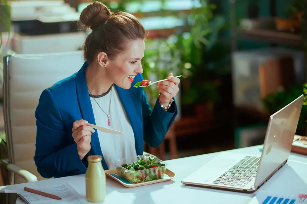 Mujer en oficina comiendo saludable entre juntas