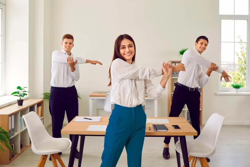 Tres colaboradores haciendo ejercicio de estiramiento en oficina