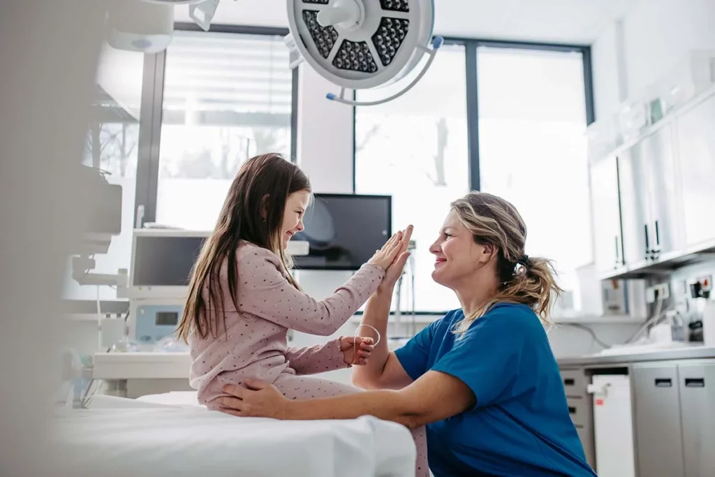 Doctora choca manos con niña después de pasar por el área de urgencias pediátricas y ser dada de alta.