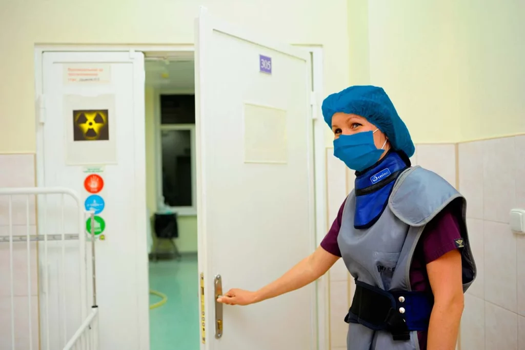 Especialista en cardiología nuclear parada frente a la puerta del área de medicina nuclear de un hospital.