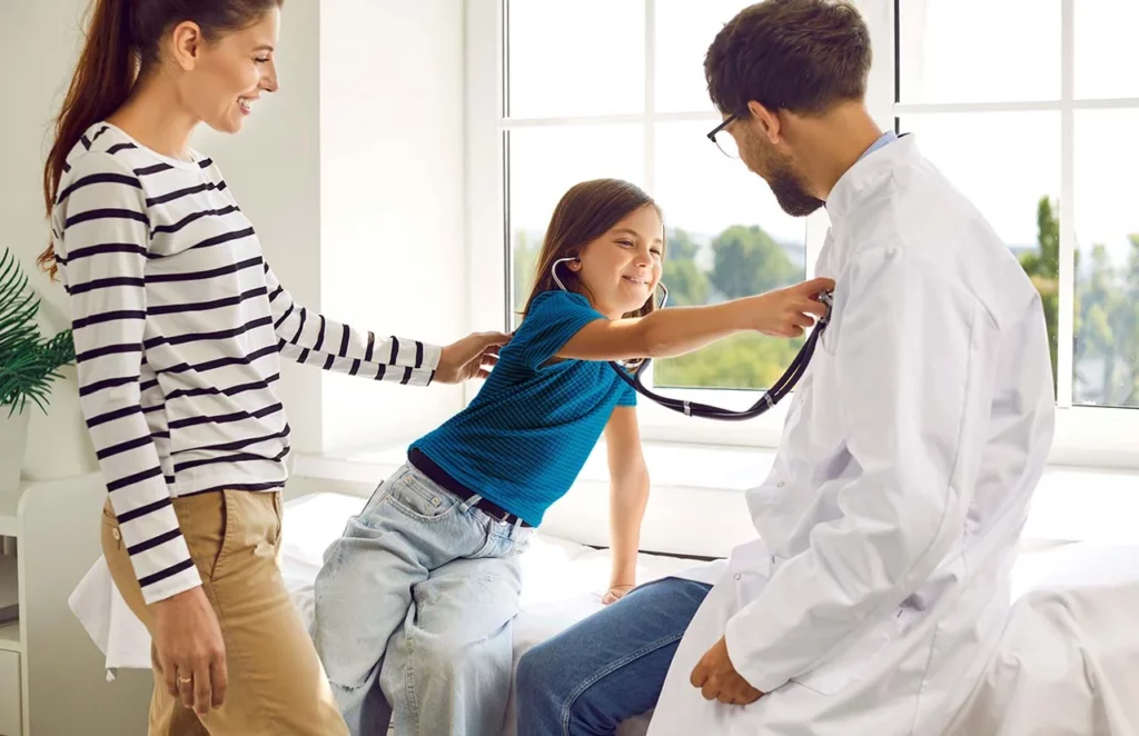 Médico nefrólogo pediatra jugando con su paciente y mamá durante la consulta.