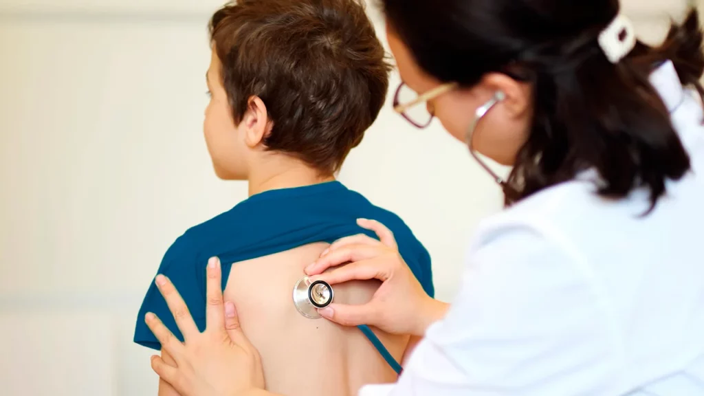 Neumólogo pediatra realizando un chequeo a los pulmones de un niño que es su paciente.